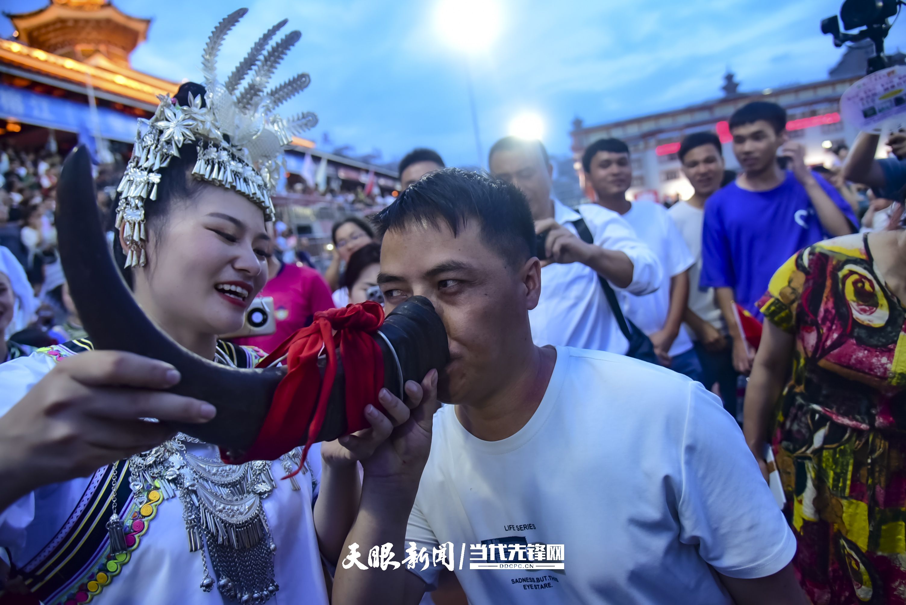 村超現(xiàn)場，當(dāng)?shù)厝罕娤蜻h道而來的游客敬酒。 潘邵平 攝.jpg